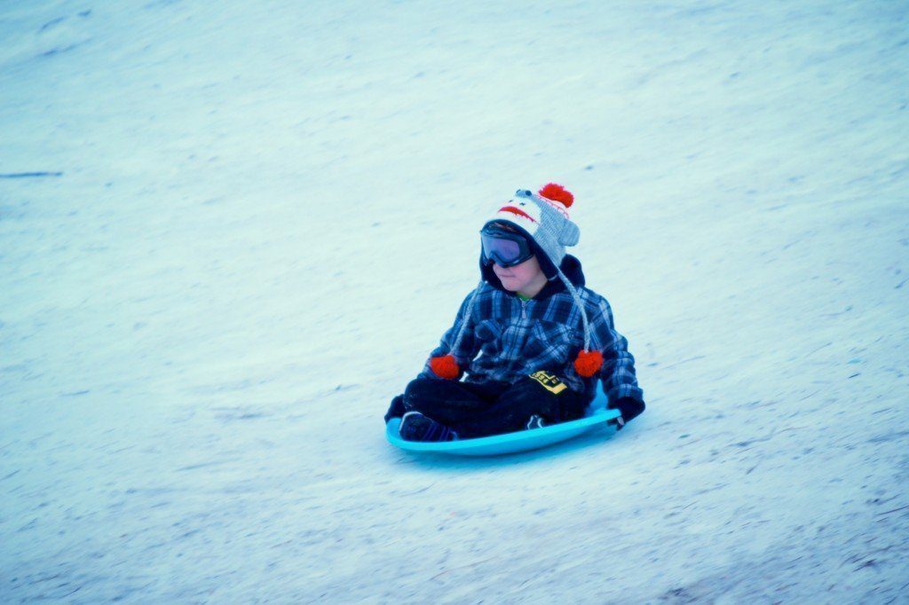 little boy sledding by Ken Kistler